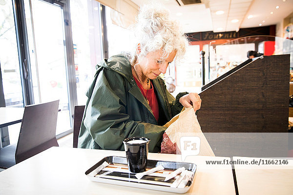 Frau im Cafe durchsucht Tasche