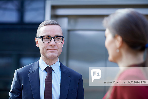 Over shoulder view of businessman approaching woman in office