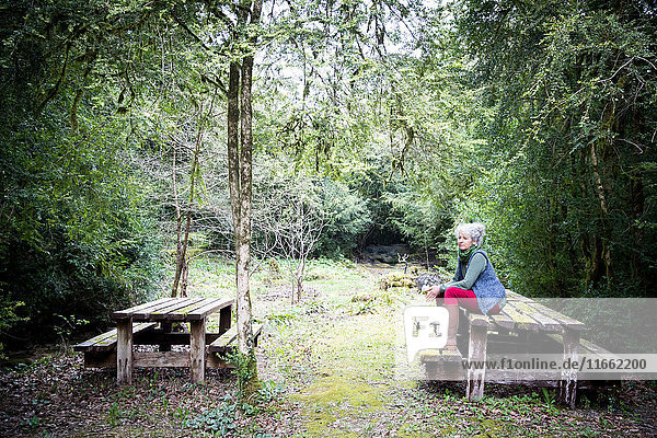 Ältere Gärtnerin macht eine Pause auf der Gartenbank