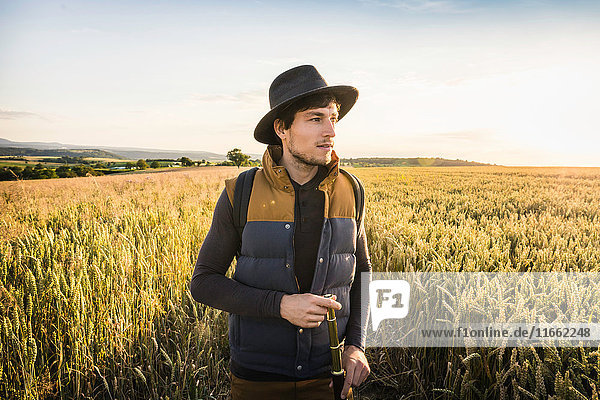 Mid adult man standing in field holding telescope Neulingen Baden-Württemberg Germany