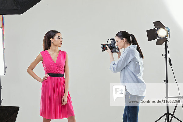 Photographer photographing fashion model in white backdrop photography studio shoot