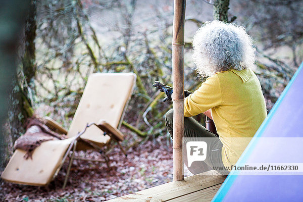 Ältere Frau schaut von der Veranda des Waldcampings
