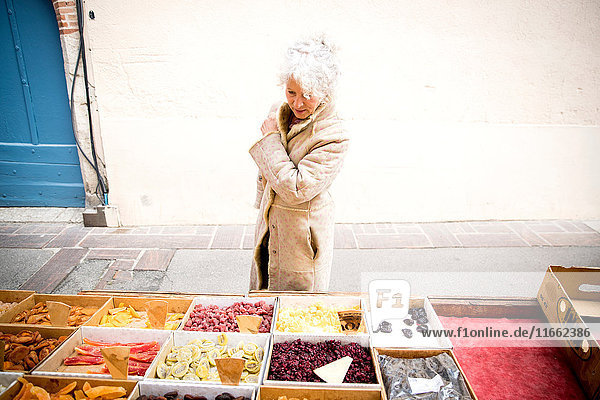 Ältere Käuferin betrachtet getrocknete Lebensmittel auf dem lokalen französischen Markt
