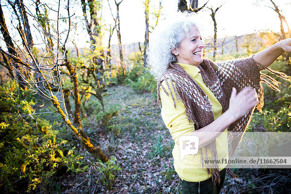Happy mature woman in woodland scrub at sunset