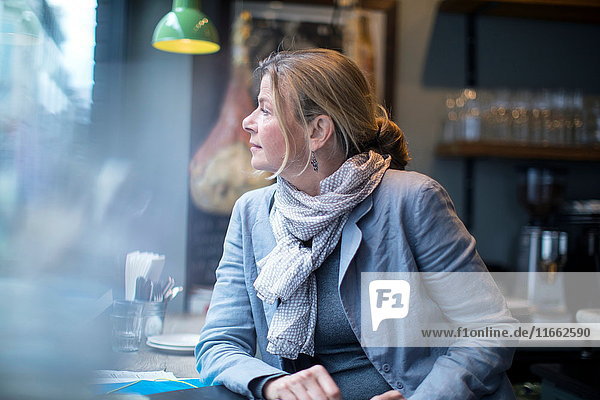 Reife Geschäftsfrau wartet im Restaurant-Fenstersitz