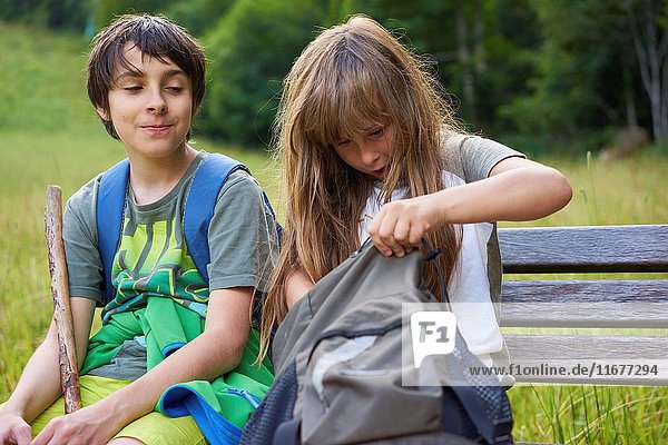 Young boy is smiling about a girl who is searching in her backpack