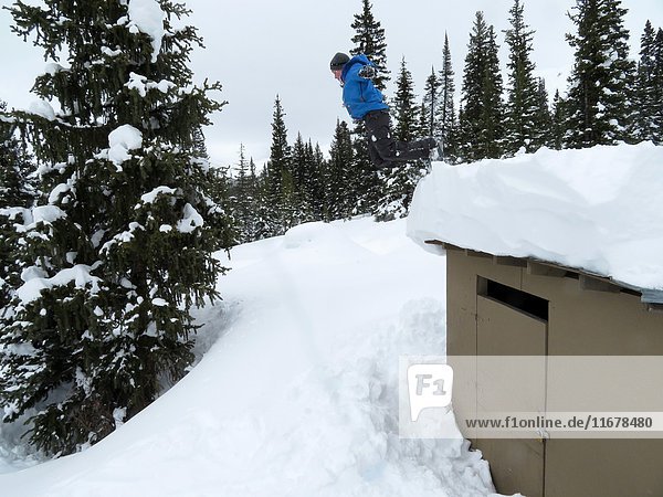 A boy  13  jumps from a roof into snow in Winter in Jasper National Park  Alberta  Canada.