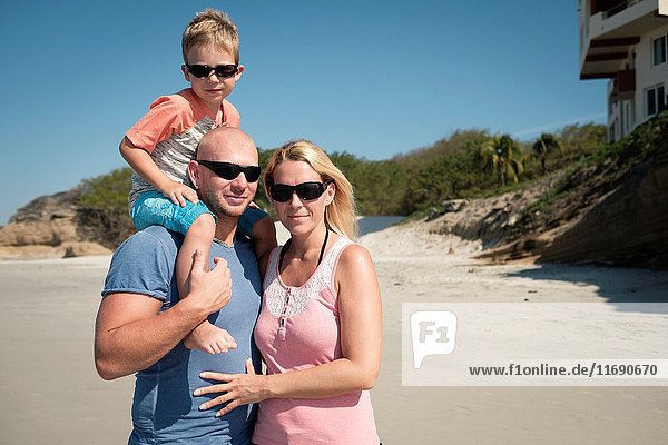 Family of 3 on the a beach father - mother - toddler child.