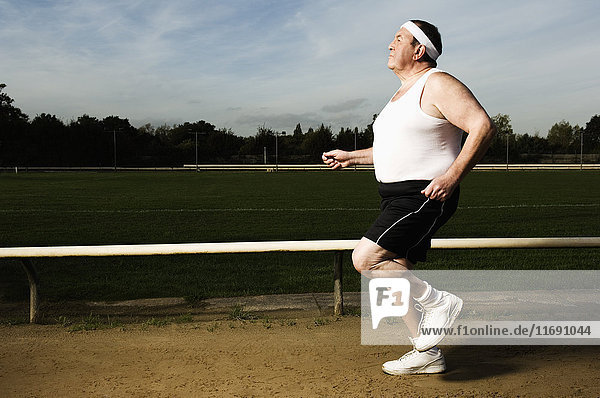 Ältere Männer  die in Sportkleidung und mit Schweißband auf einer Rennstrecke laufen.