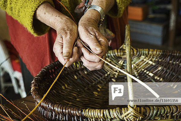 Close up of woman weaving a basket in weaver's workshop.