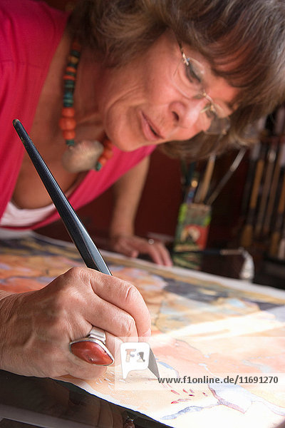 Ältere Frau malt mit Aquarellfarben