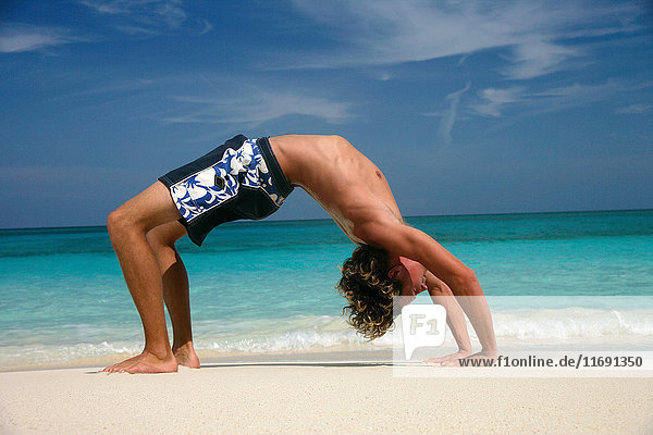 Man practicing yoga on tropical beach