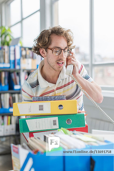 Junger Mann benutzt Telefon im Kreativbüro
