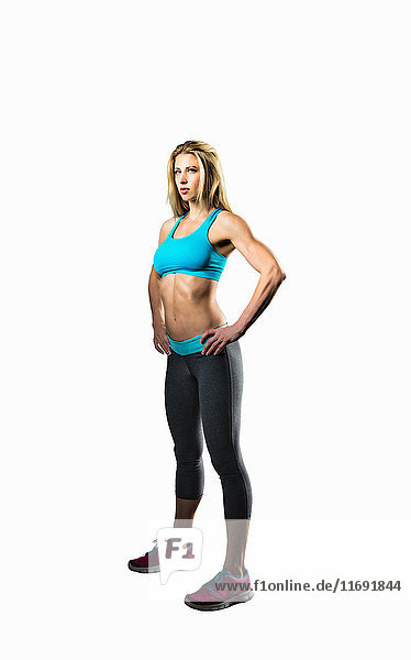 Young woman in sportswear standing with hands on hips  studio shot