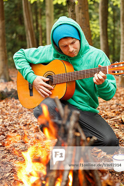 Mann spielt Gitarre am Lagerfeuer