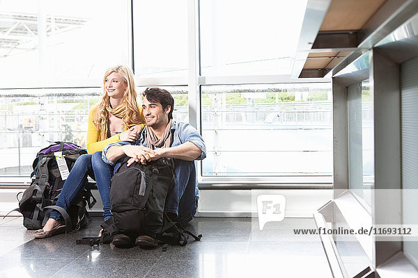 Auf dem Boden sitzendes Ehepaar im Flughafen