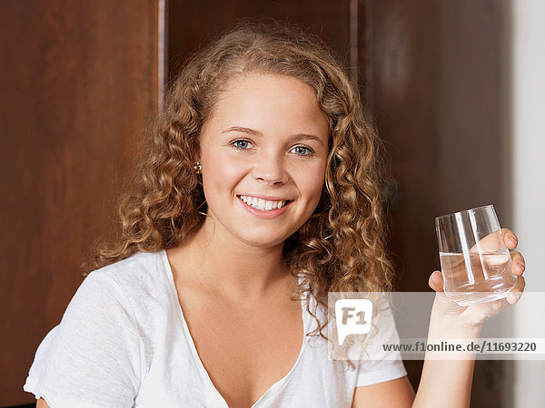 Porträt einer jungen Frau  die ein Glas Wasser hält.