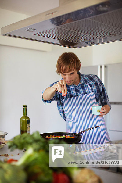 Man sprinkling spices on cooking
