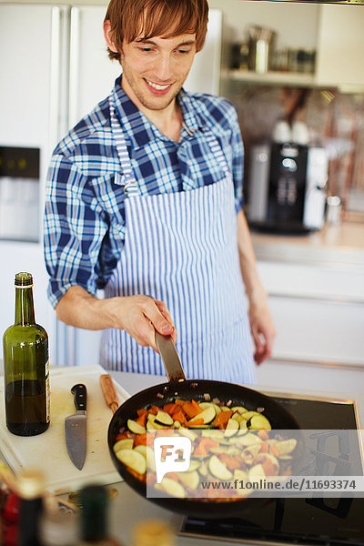 Man frying vegetables in kitchen