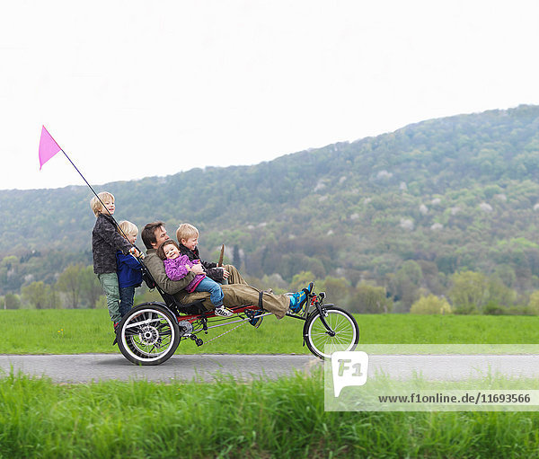 Familie fährt gemeinsam auf einem dreirädrigen Fahrrad