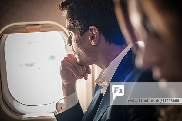 Männlicher Passagier schaut aus dem Flugzeugfenster