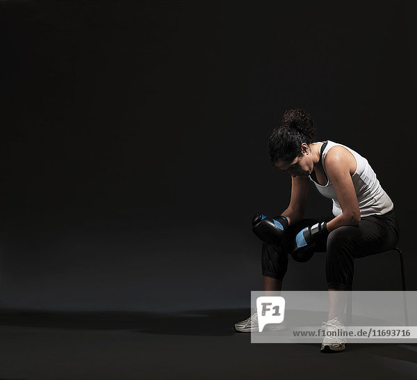 Weibliche Boxerin vor schwarzem Hintergrund sitzend