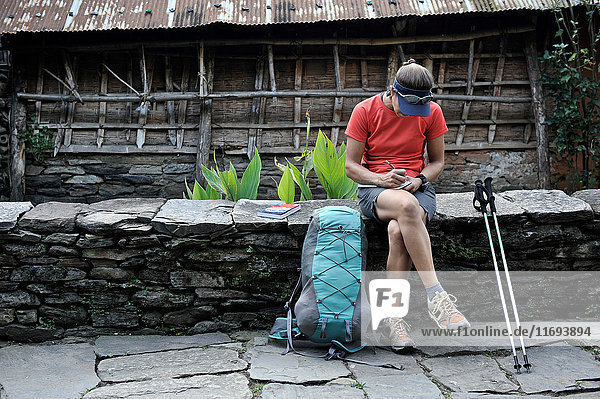 Woman stops for a break along stone-paved street  Ngadi  Nepal