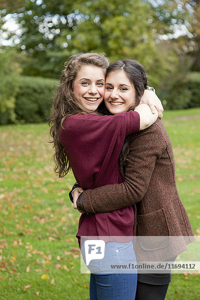 Lächelnde Mädchen umarmen sich im Park