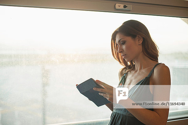 Junge Frau mit digitalem Tablett am Fenster