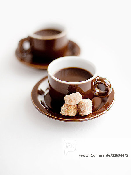 Fresh coffee in cups with brown sugar lumps