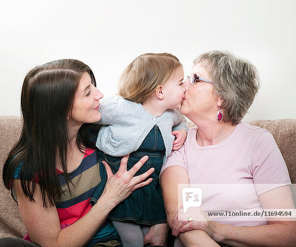 Familie in drei Generationen  Enkelin küsst Großmutter
