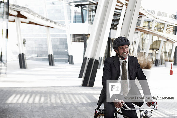 Mittlerer erwachsener Geschäftsmann auf dem Fahrrad in der Stadt