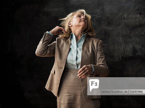 Businesswoman tossing hair by blackboard