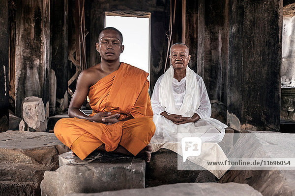 Senior and young monk meditating in temple in Angkor Wat  Siem Reap  Cambodia