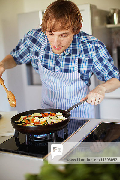 Man frying vegetables in kitchen