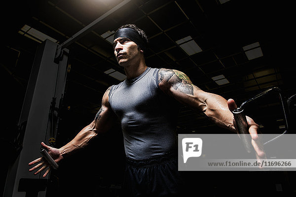 Muskulöser junger Mann  der Pulldown-Übungen im Fitnessstudio ausführt