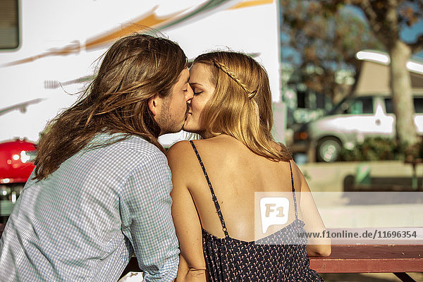 Küssende Paare am Picknicktisch im Freien