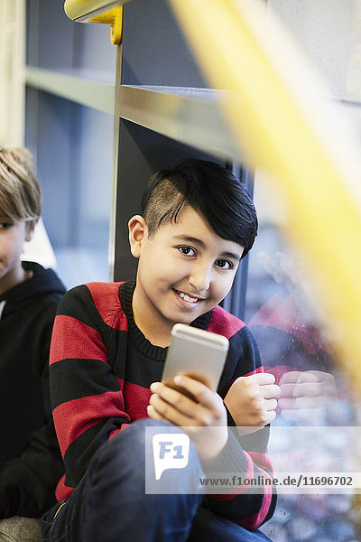 Porträt eines lächelnden Jungen mit Smartphone in der Mittelschule