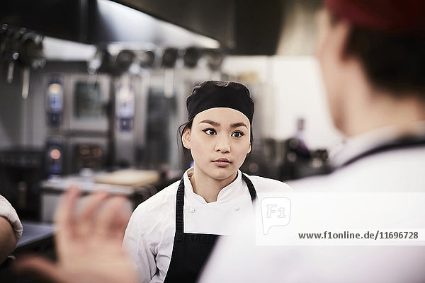 Female chef student listening to teacher in cooking school