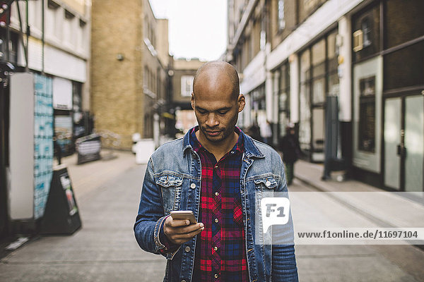 Mittlerer Erwachsener Mann mit Handy auf der Straße in der Stadt