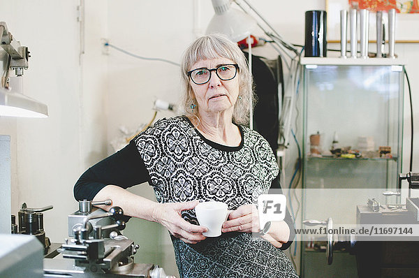 Porträt einer selbstbewussten Seniorin mit Kaffeetasse im Juweliergeschäft