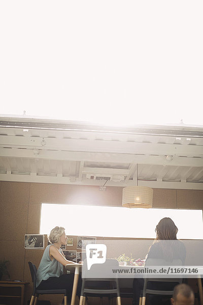 Geschäftsfrauen diskutieren am Schreibtisch im tragbaren Bürotruck an sonnigen Tagen