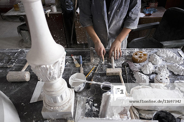 Hands of Caucasian sculptor holding tools