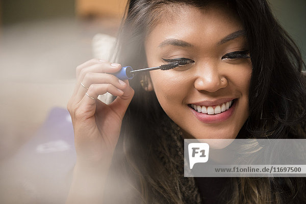 Mixed Race woman applying mascara