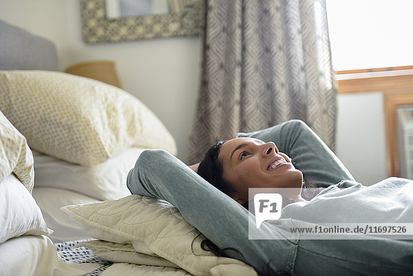 Smiling Hispanic woman laying on bed
