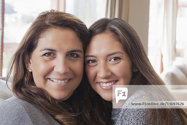 Smiling Hispanic mother and daughter posing cheek to cheek