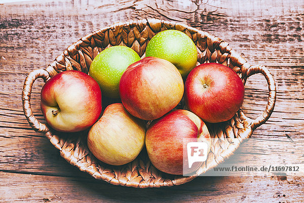 Korb mit Äpfeln auf Holztisch
