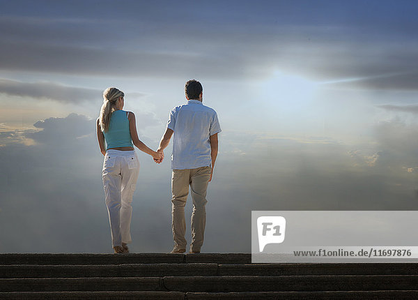 Caucasian couple admiring scenic view of clouds from staircase