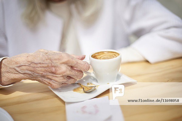 Hand of older Caucasian woman drinking coffee