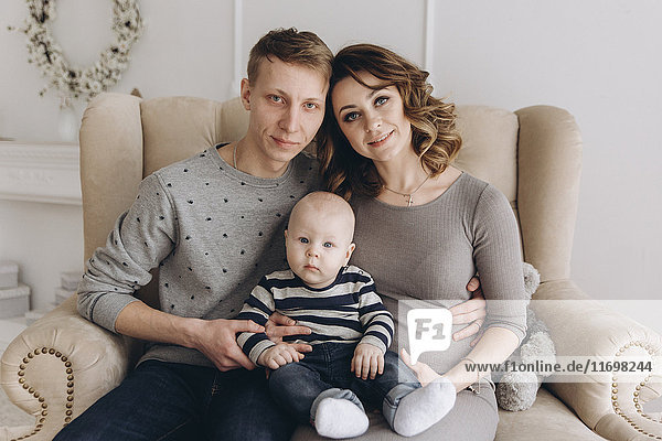 Porträt einer kaukasischen Mutter und eines Vaters auf dem Liebessitz mit ihrem kleinen Sohn